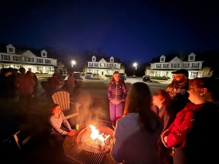 Group chatting by fire pit at night