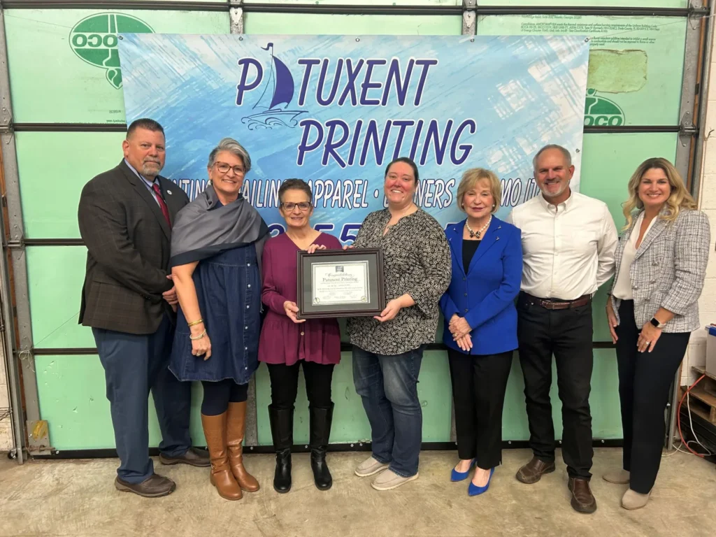 Group poses with company certificate at event.