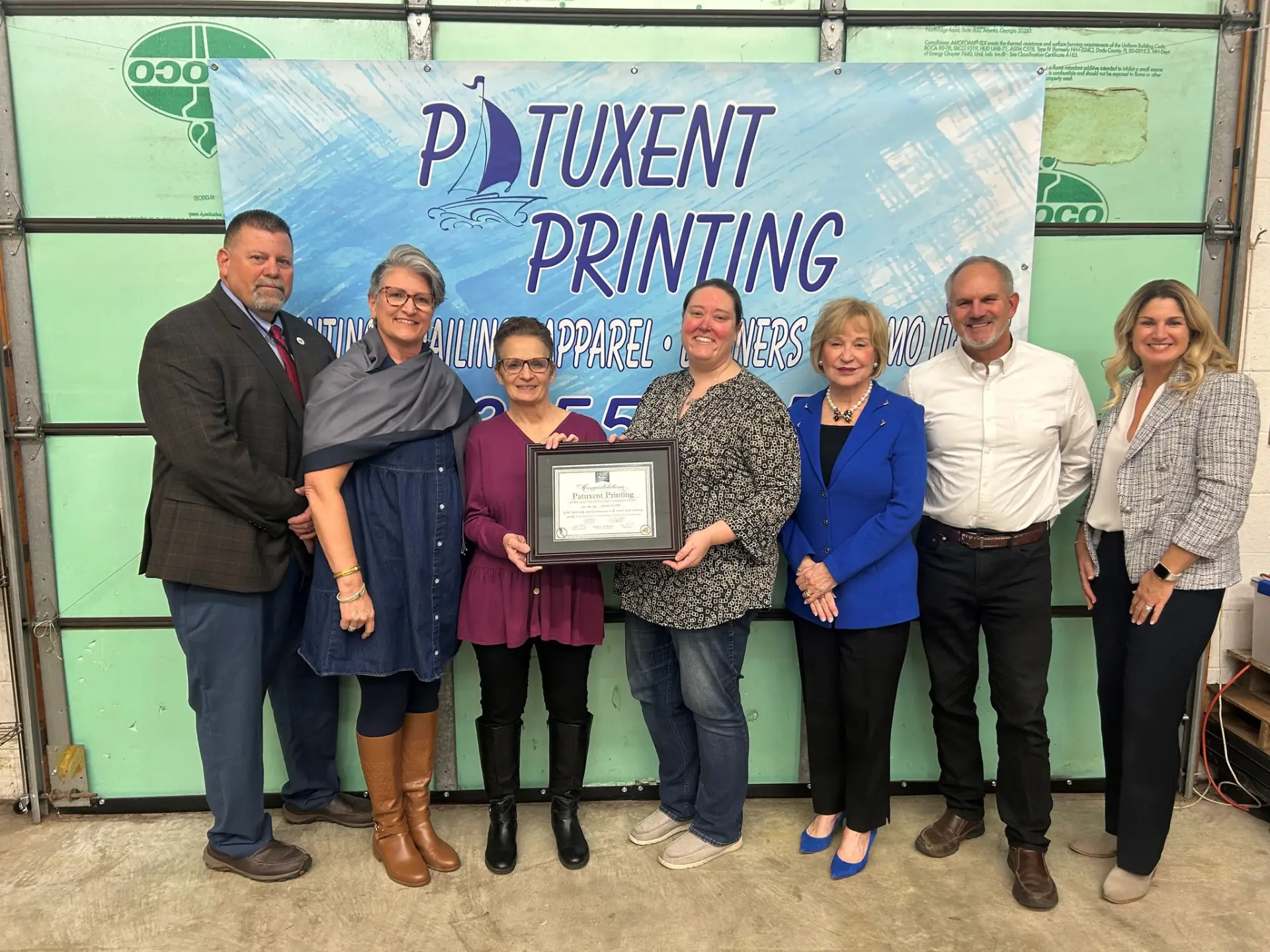 Group poses with company certificate at event.