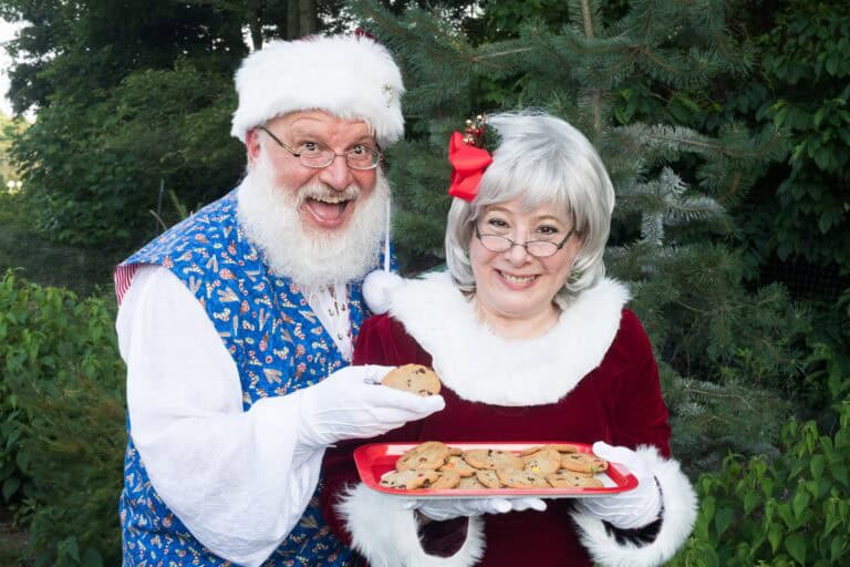 Couple dressed as Santa and Mrs. Claus with cookies.
