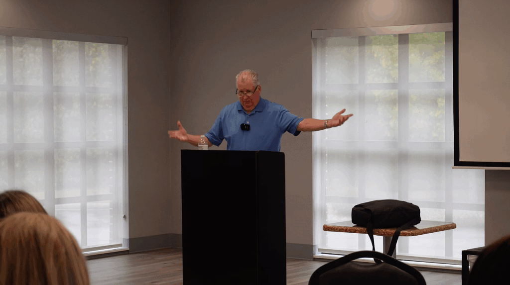 Man speaking at a podium in conference room.