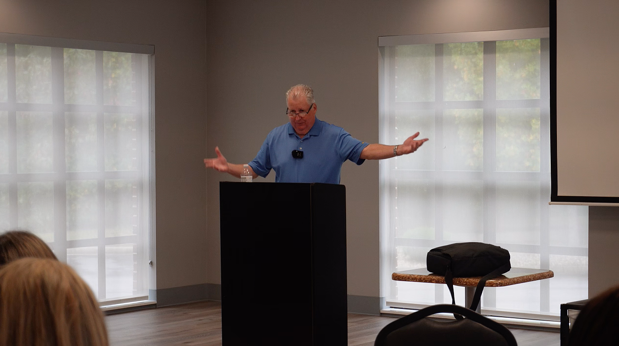 Man speaking at a podium in conference room.